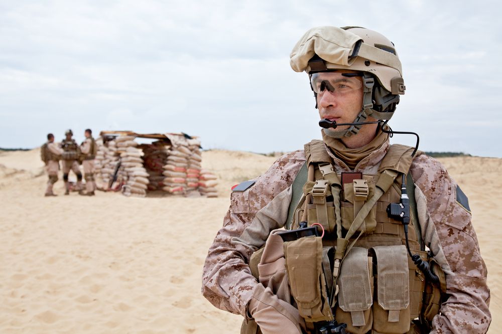 A soldier wears safety glasses in the desert.